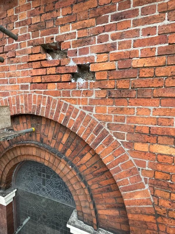 Brick arch repairs. Installing stainless steel wall ties and slate packing the arch as advised by Historic England at Westgate Unitarian Chapel in Wakefield. West Yorkshire